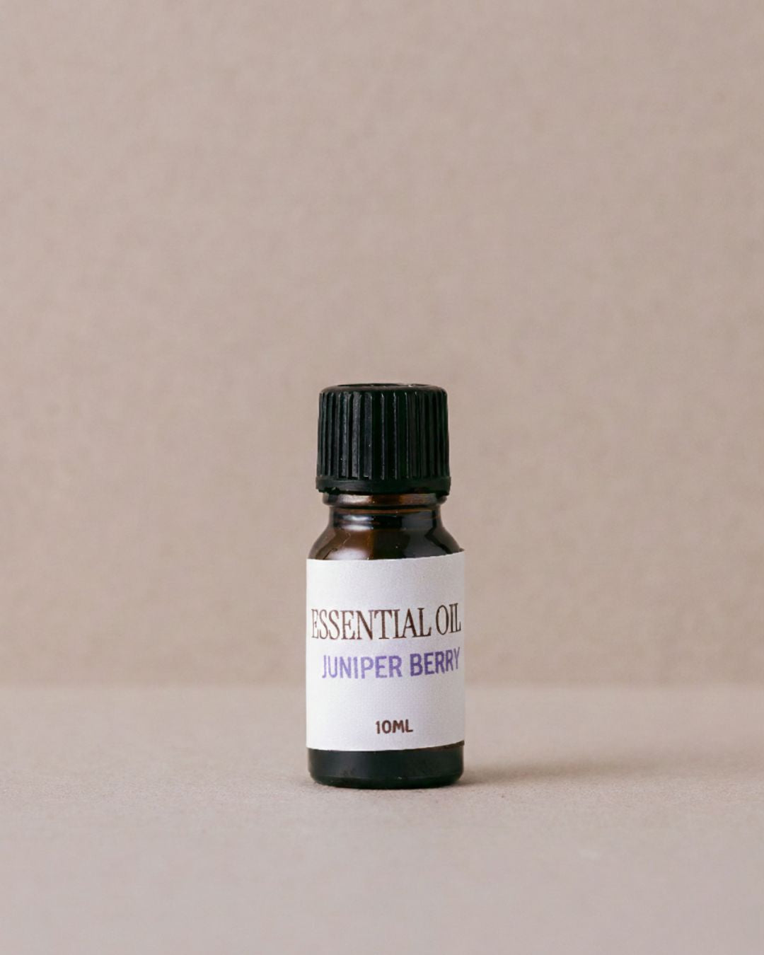 Bottle of Juniper Berry essential oil on a beige background