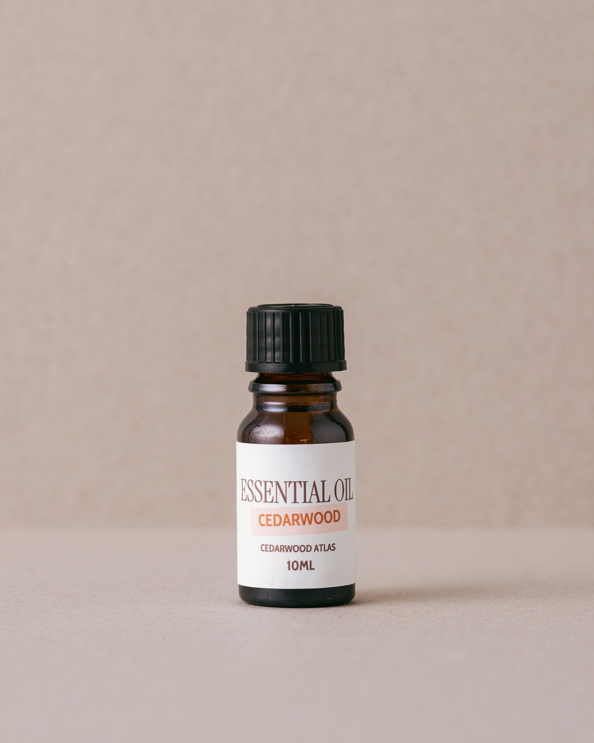 cedarwood essential oil in a small glass bottle on beige background