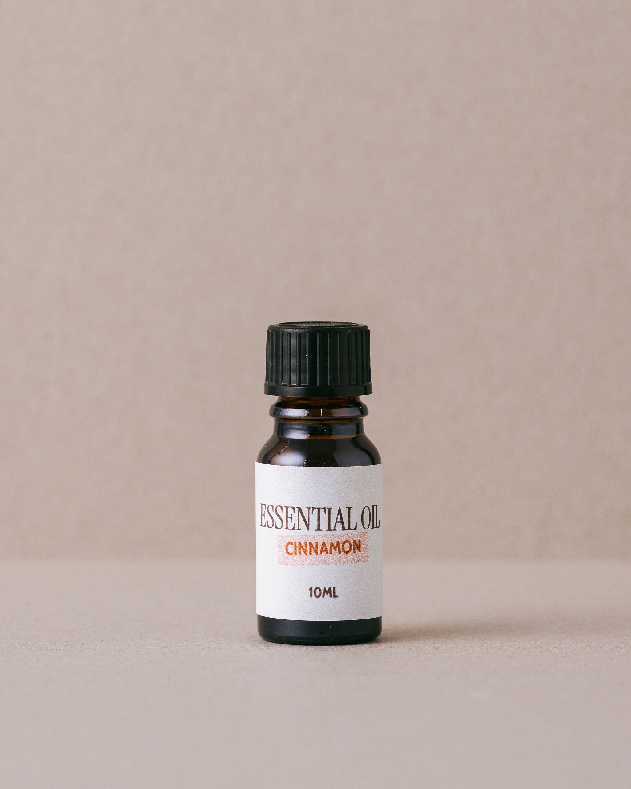 cinnamon essential oil in a glass bottle on a beige background