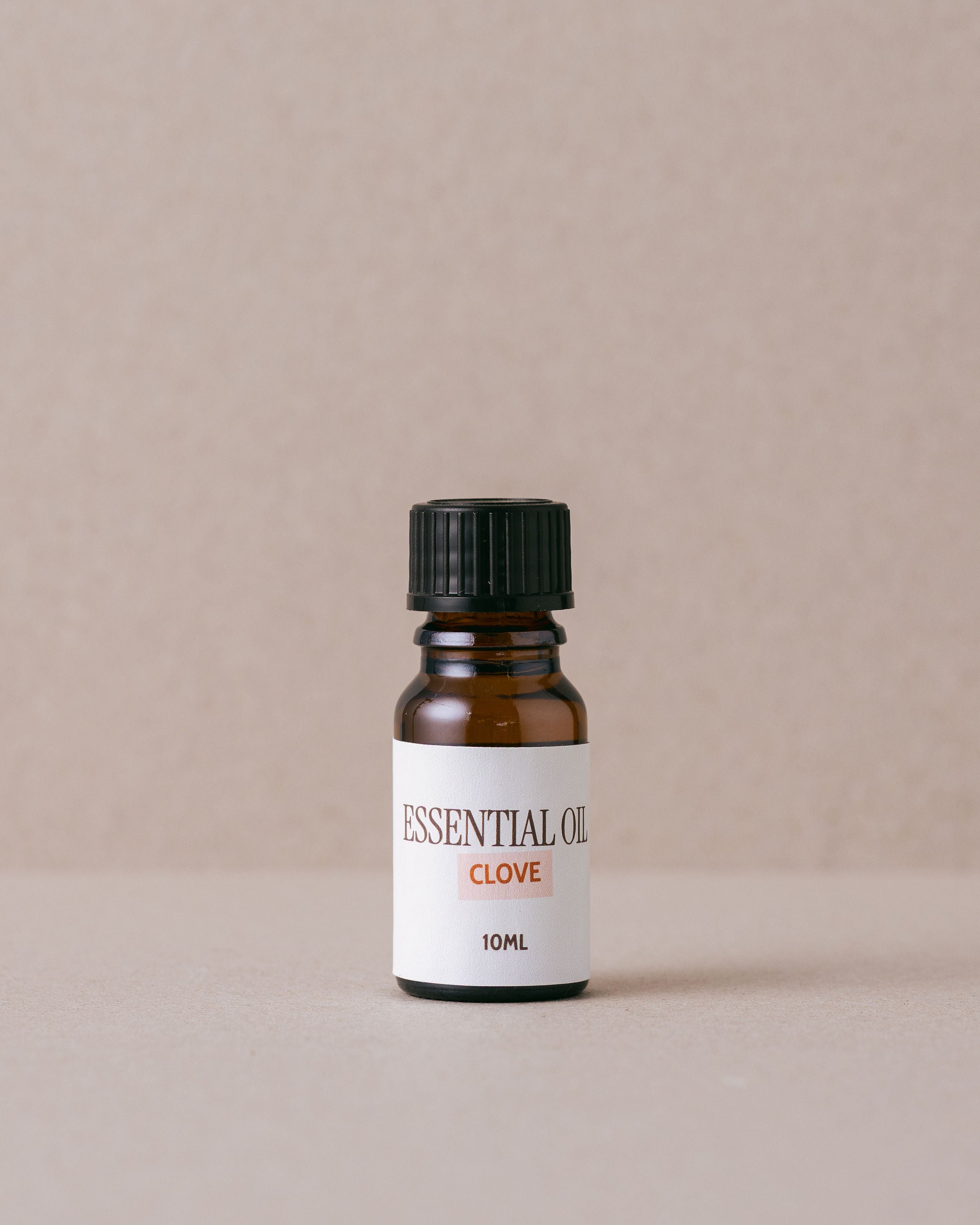 Bottle of clove essential oil on a beige background