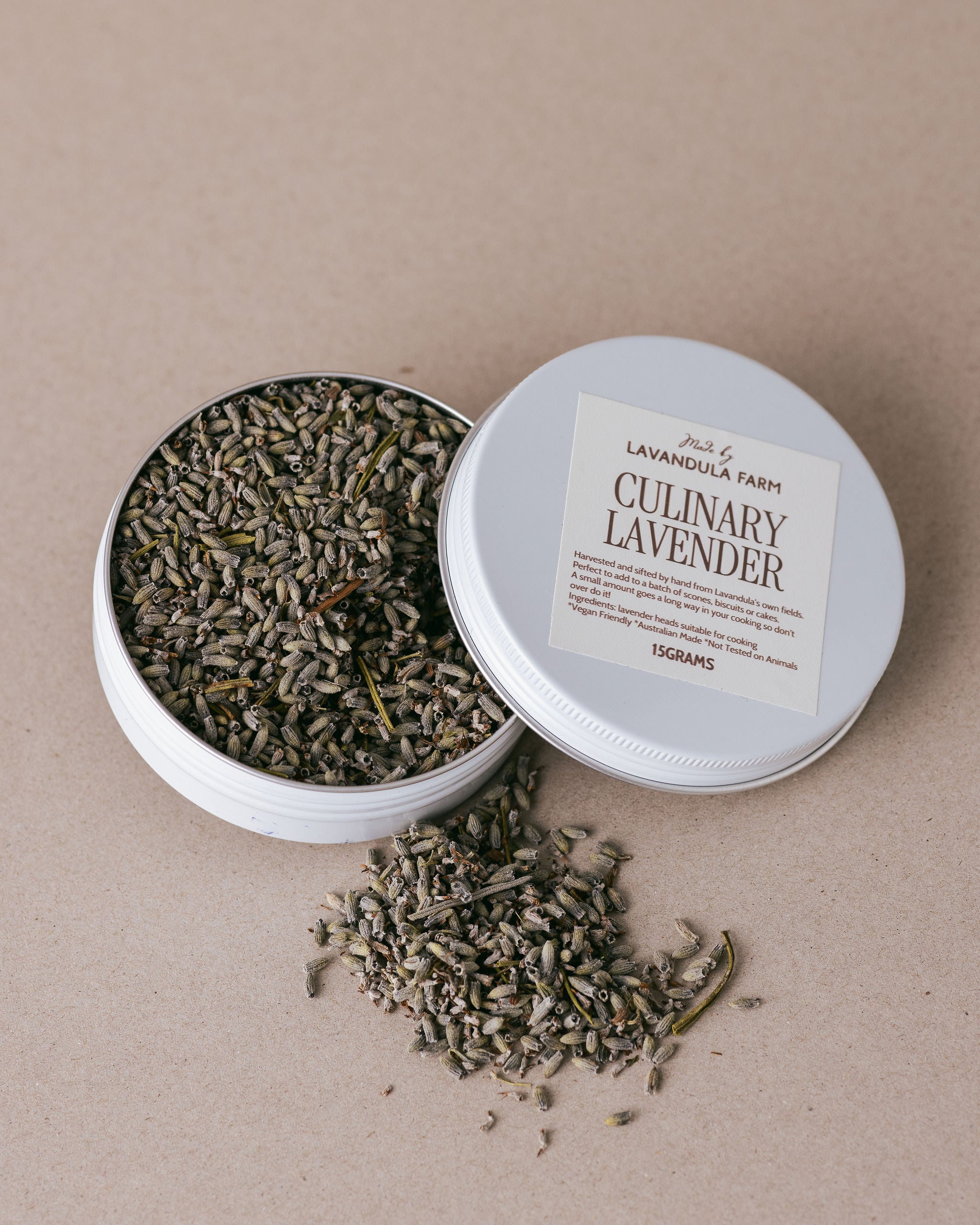 Open tin of culinary lavender with a label on a beige background
