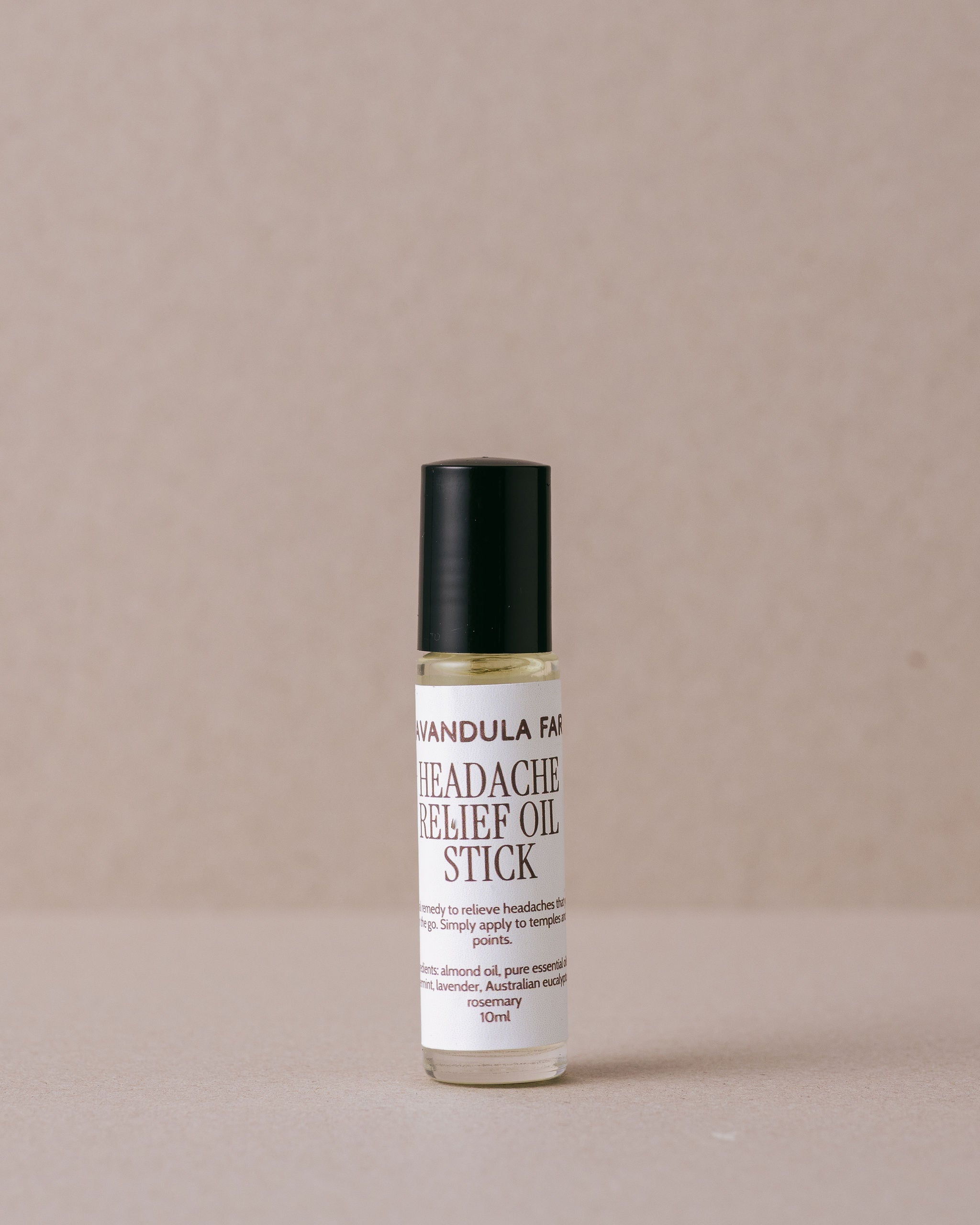 Roll-on bottle of headache relief oil stick on a beige background