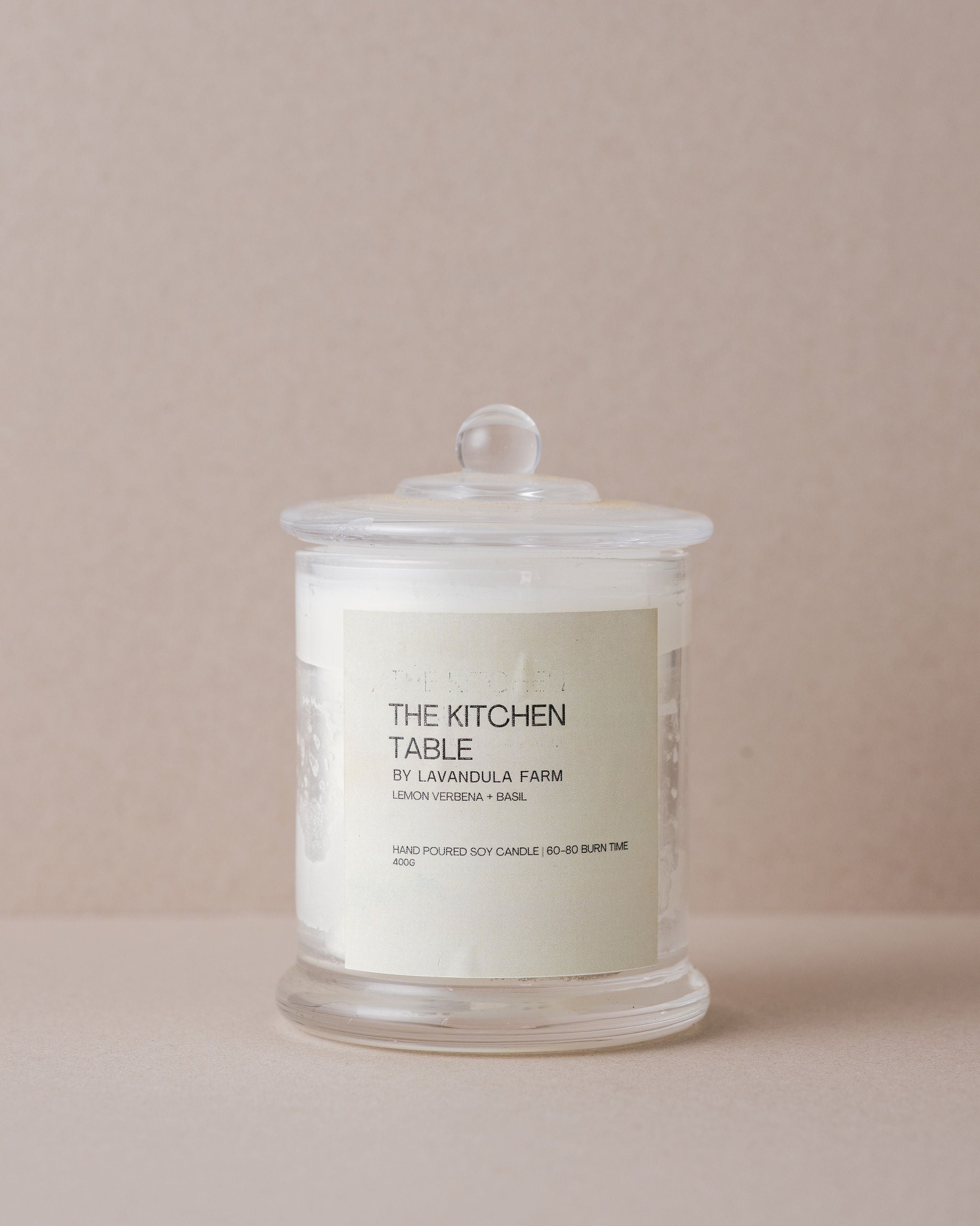 soy candle in a glass container with lid on a beige background