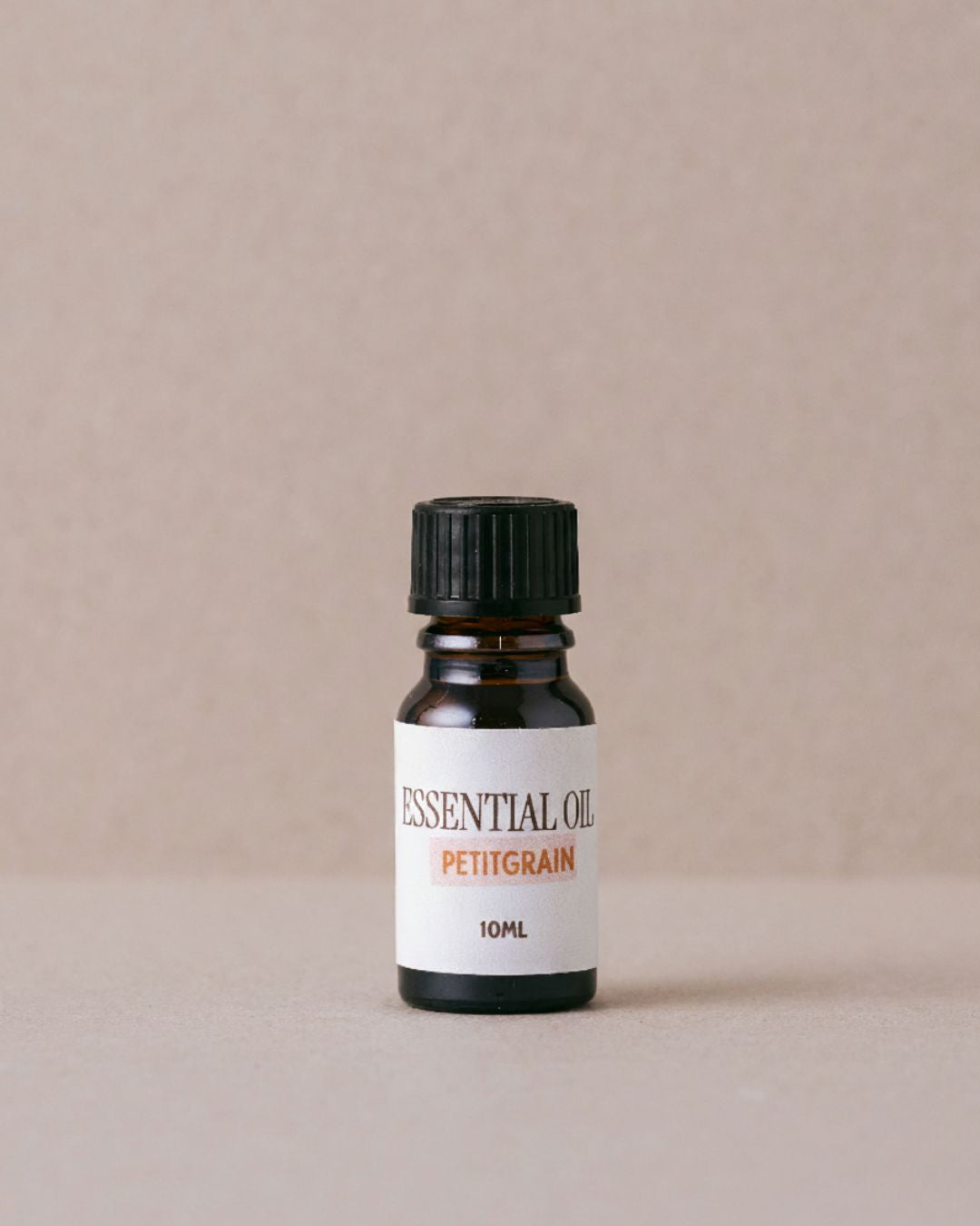 Petitgrain essential oil bottle on a beige background