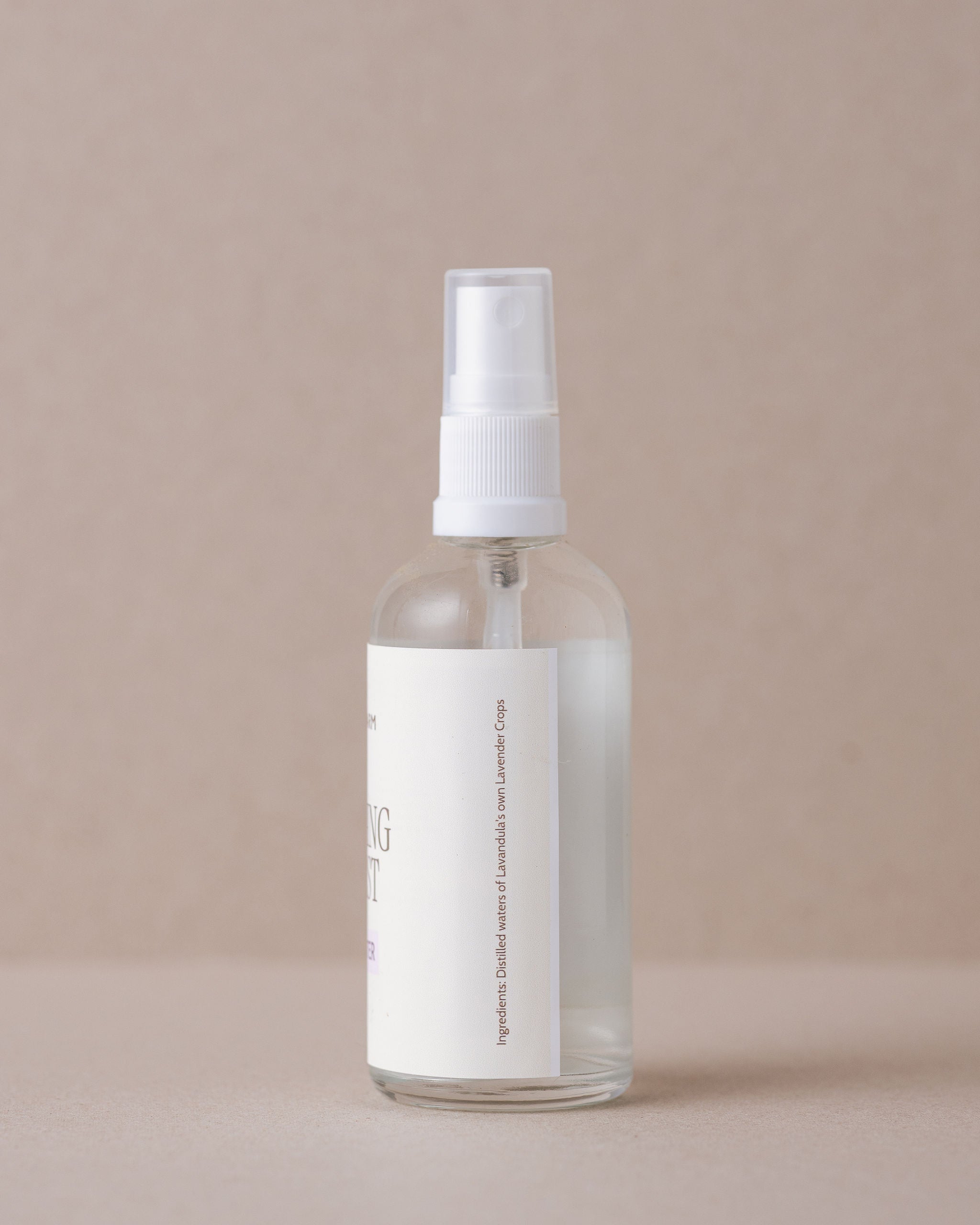 Clear spray bottle with a white label on a beige background
