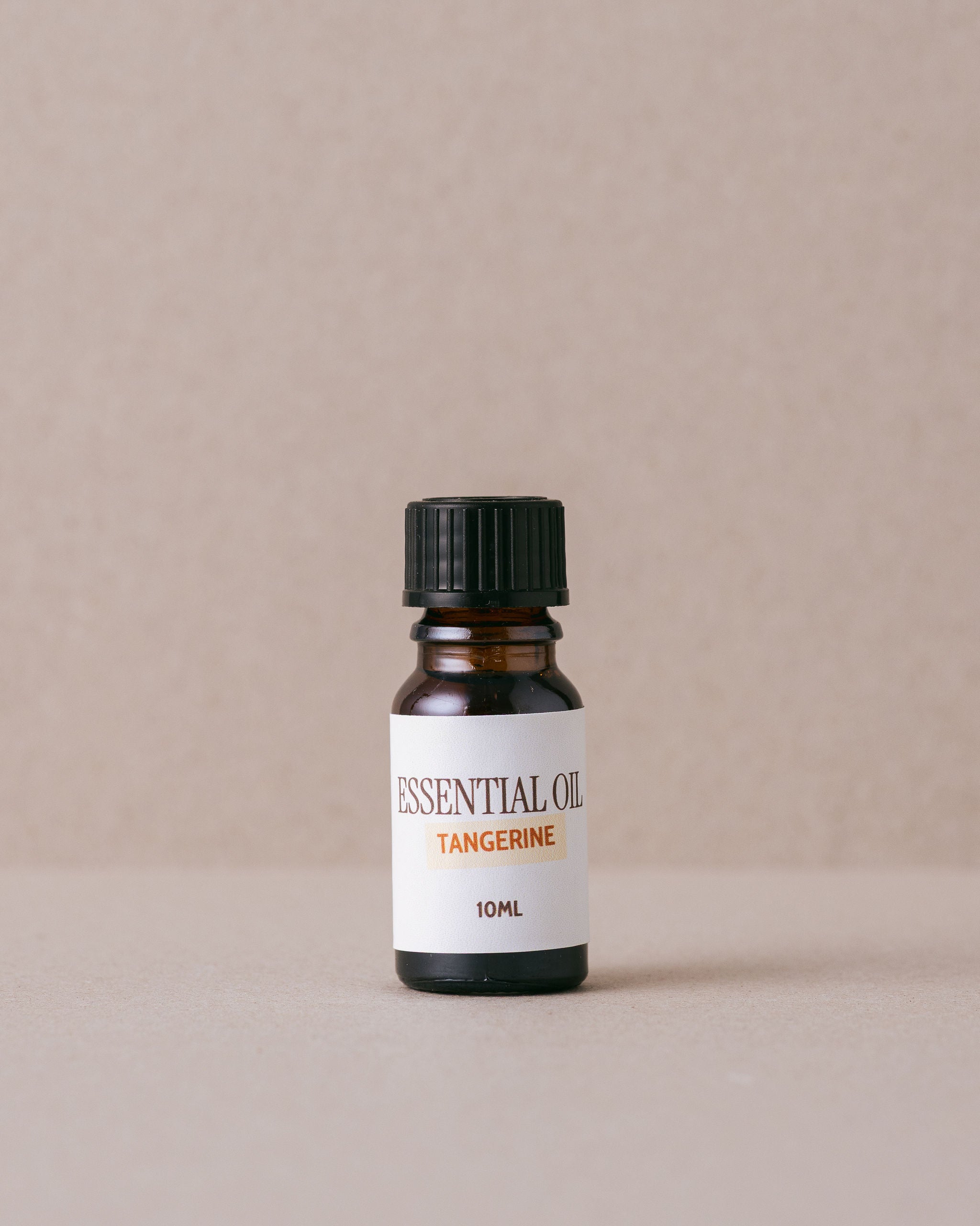 tangerine essential oil bottle on a beige background