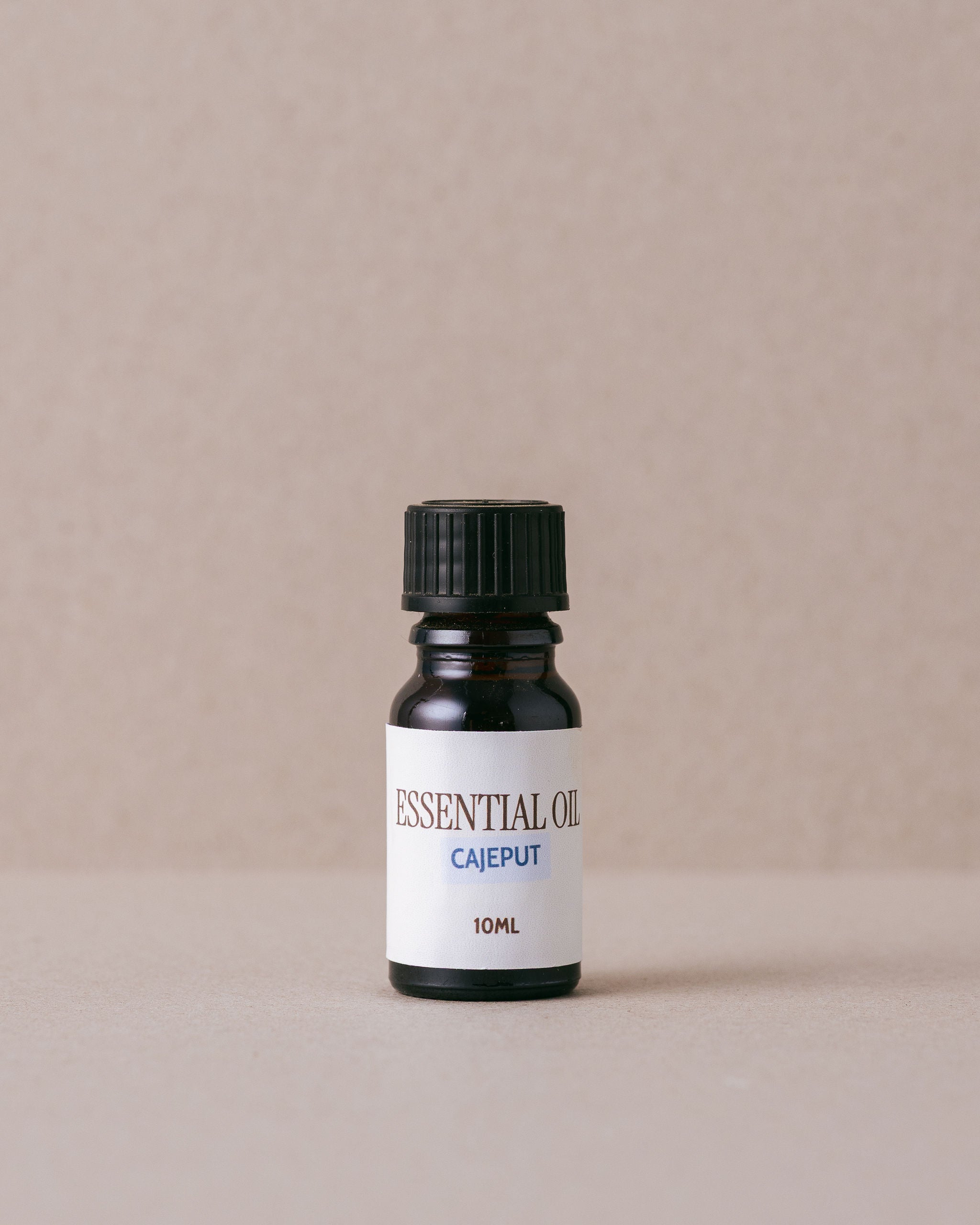 Bottle of essential oil labeled 'Cajeput' on a beige background