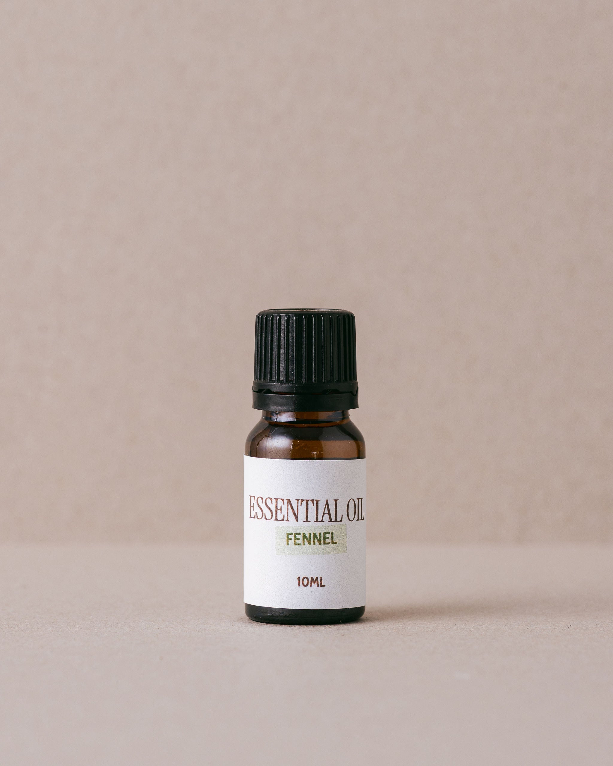 small glass bottle of fennel essential oil on a beige background