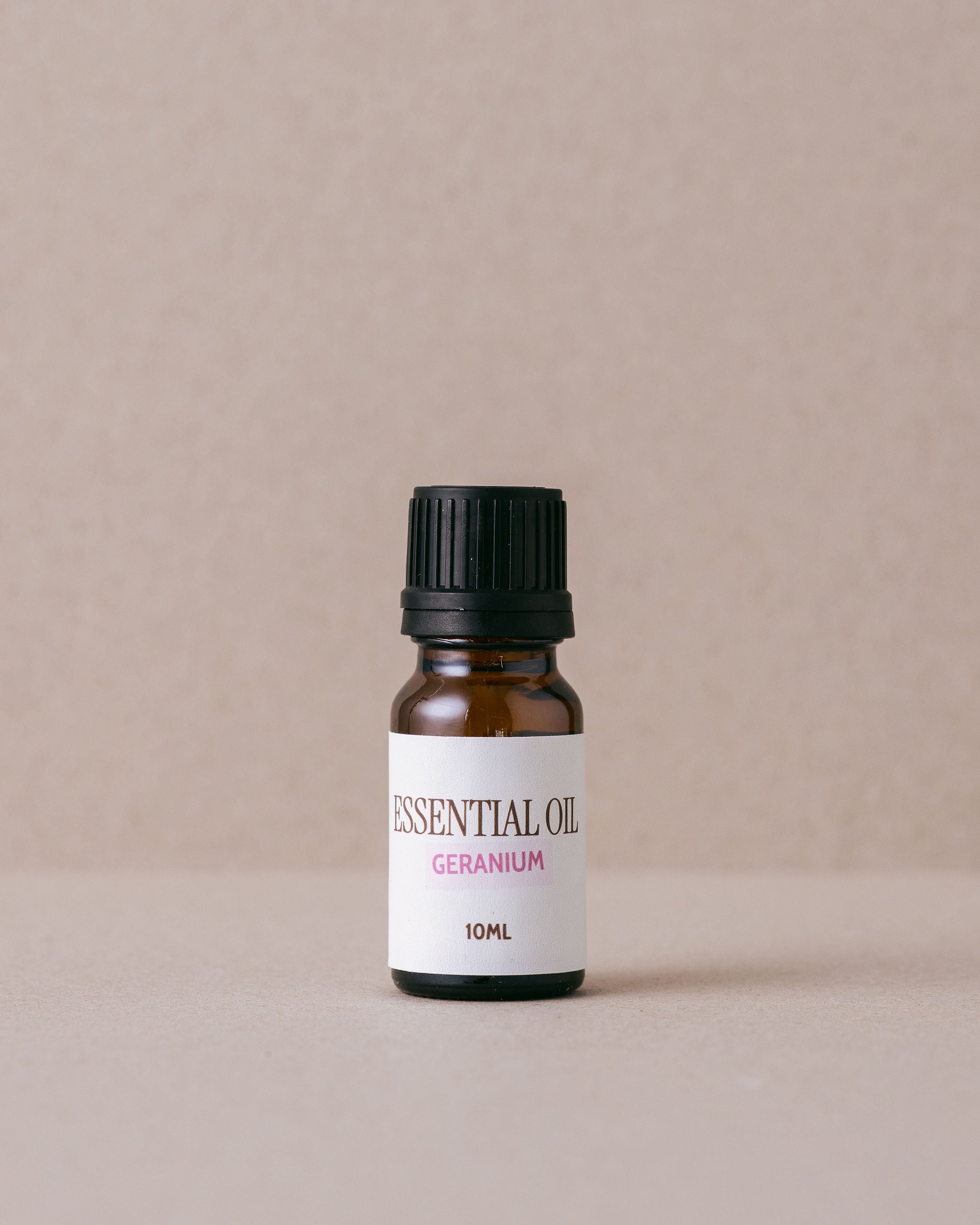 geranium essential oil in a glass bottle on a beige background