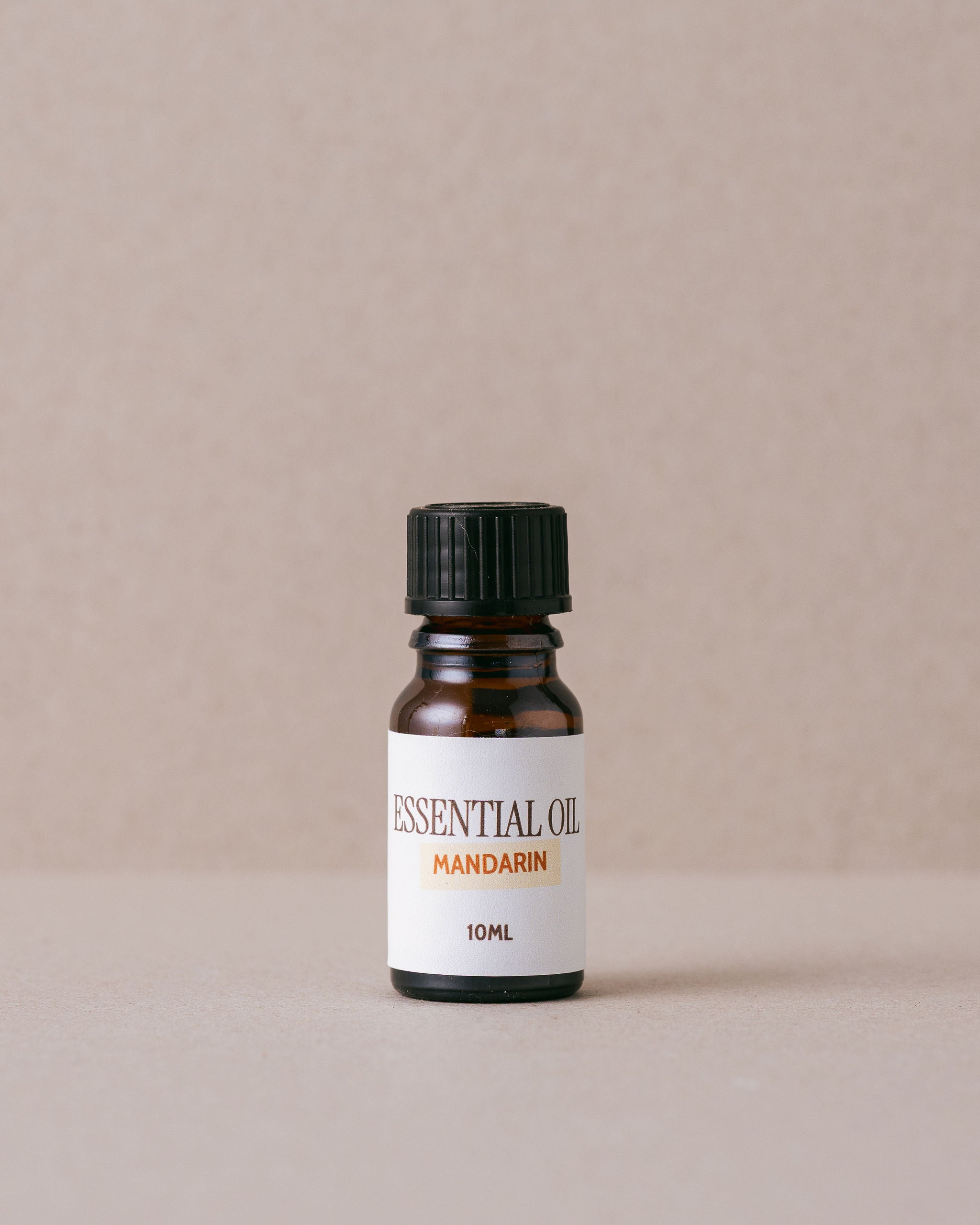 Bottle of Mandarin essential oil on a beige background