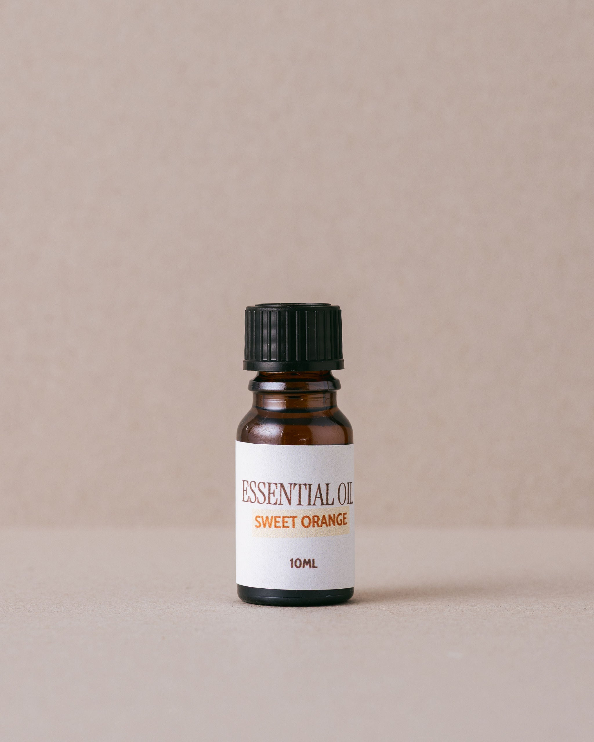 sweet orange essential oil in a bottle on a beige background