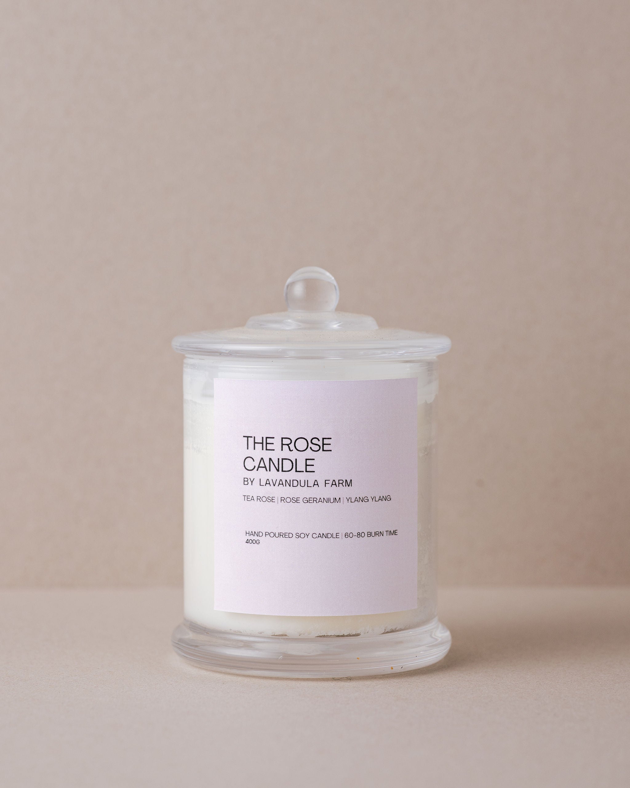 rose soy candle in glass container with lid on a beige background