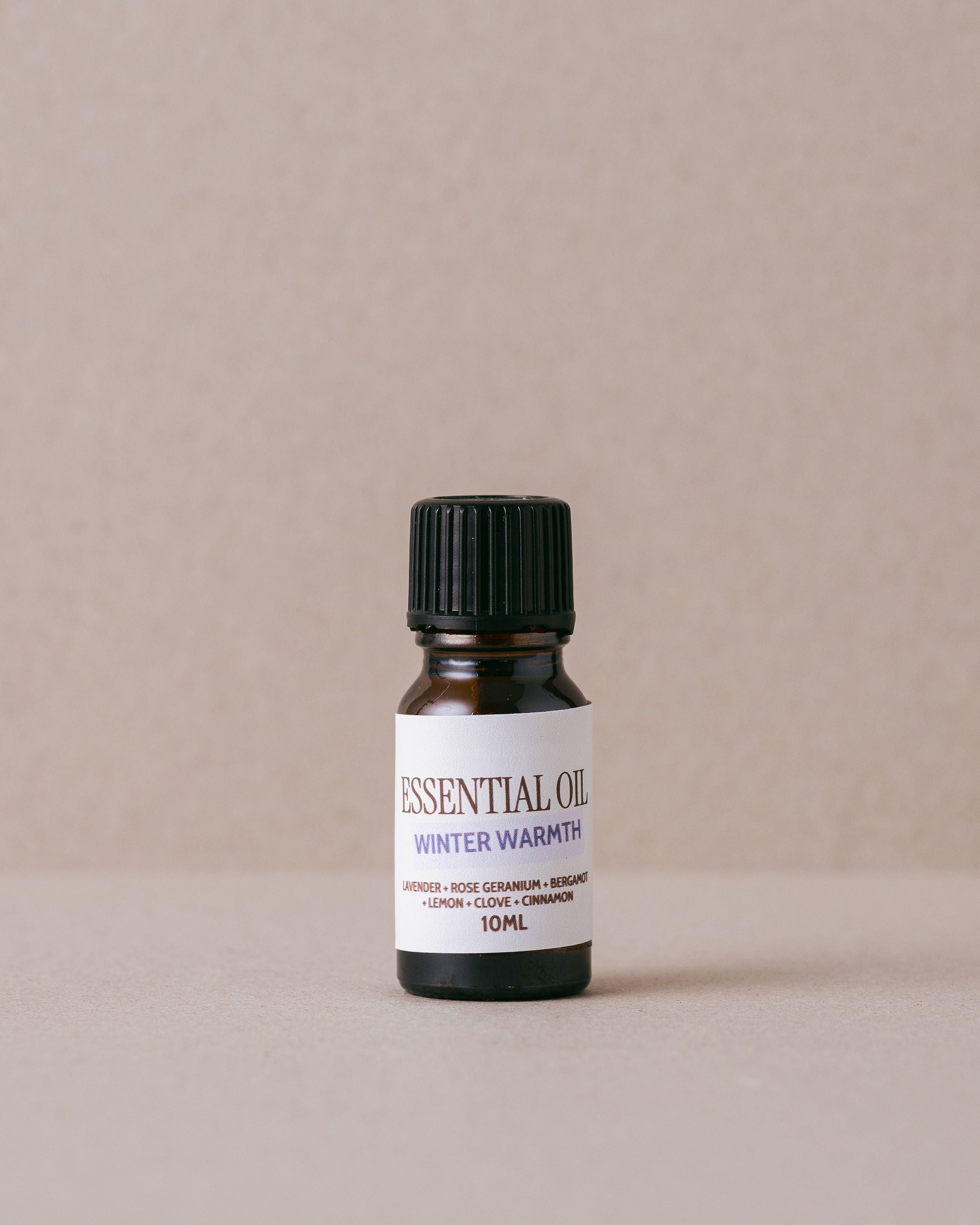 Essential oil bottle labeled 'Winter Warmth' on a beige background